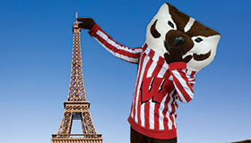 Bucky Badger standing next to the Eiffel Tower