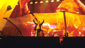 Band performing with bright orange and yellow lights at a concert.