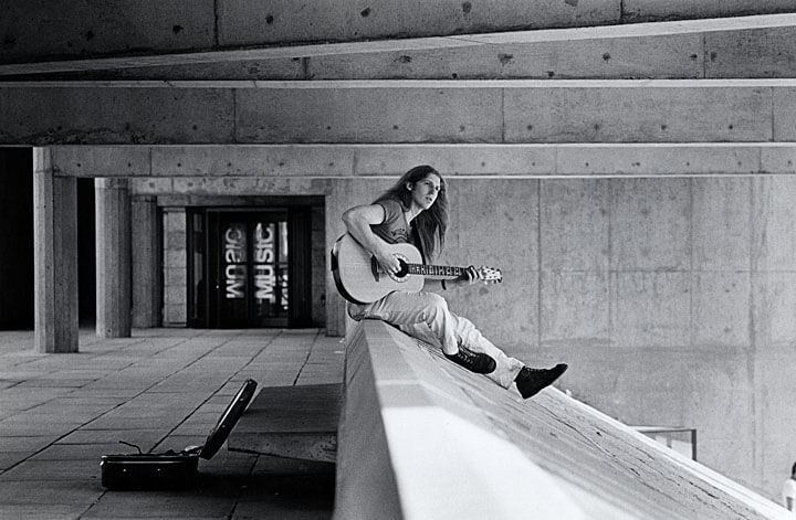 Student playing guitar outside the Humanities building.