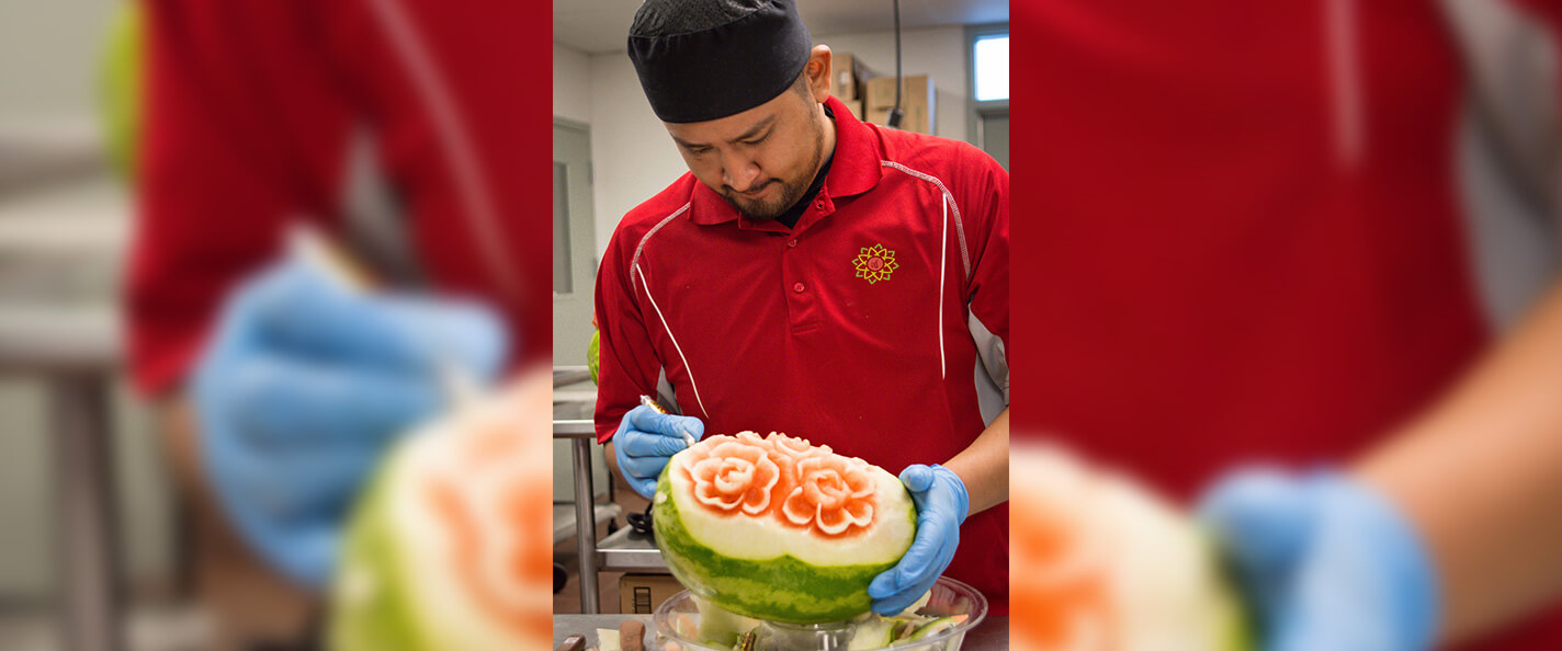 Valle carves flowers into a watermelon.