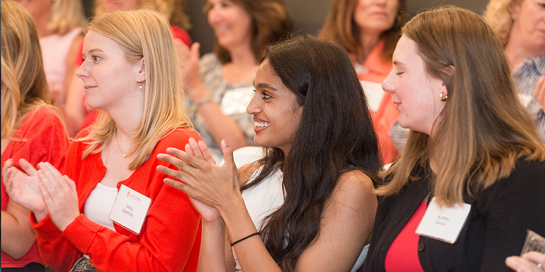 Young UW alumni applaud while listening to a speaker.
